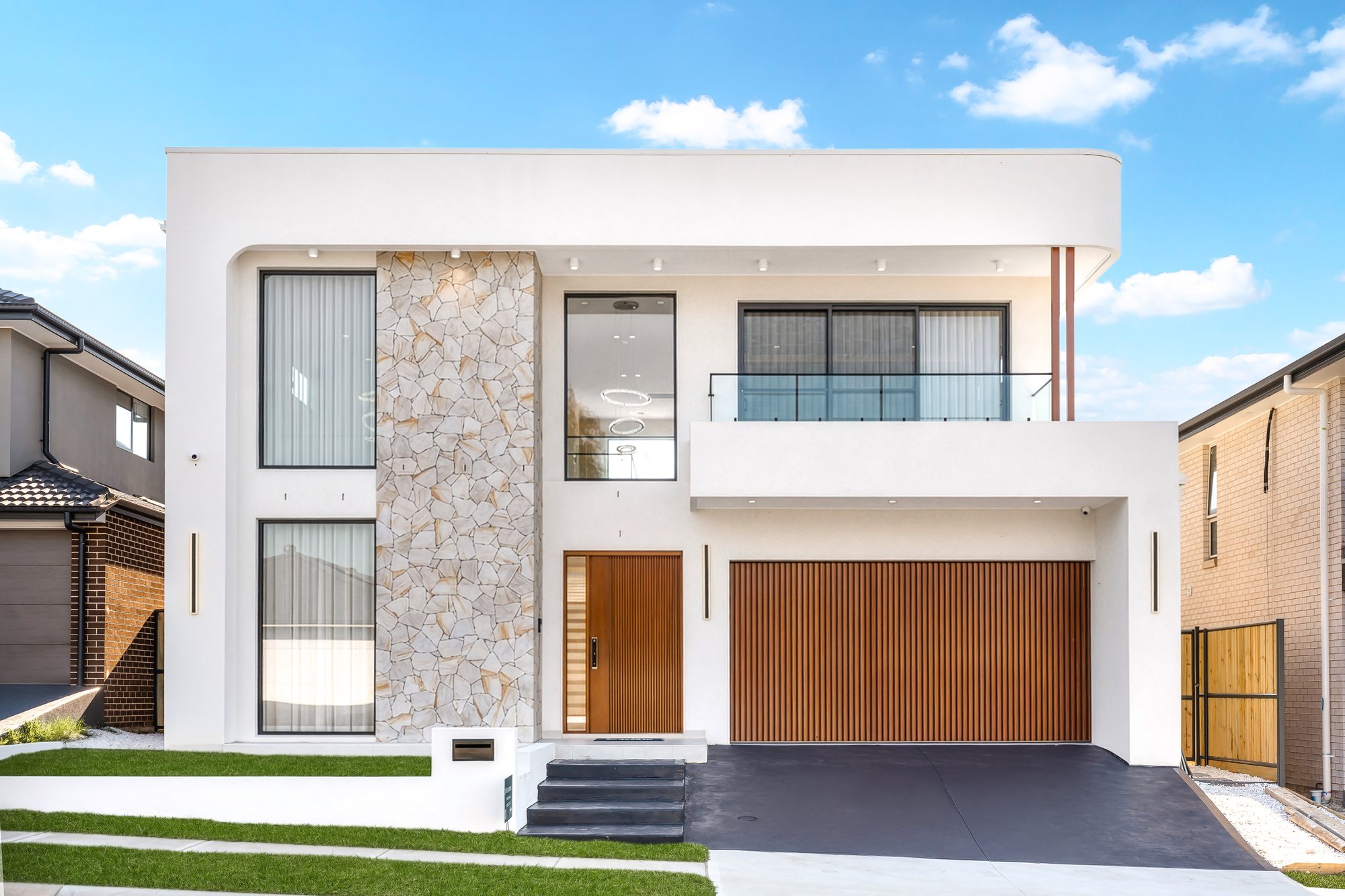 Double-storey home at Gelderland Avenue, Box Hill, with a white rendered façade, a stacked-stone feature wall, a timber front door and a timber-look garage door